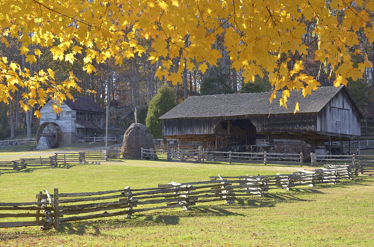 Cantilever barn and grist mill under fall leaves at the Museum of Appalachia in Tennessee