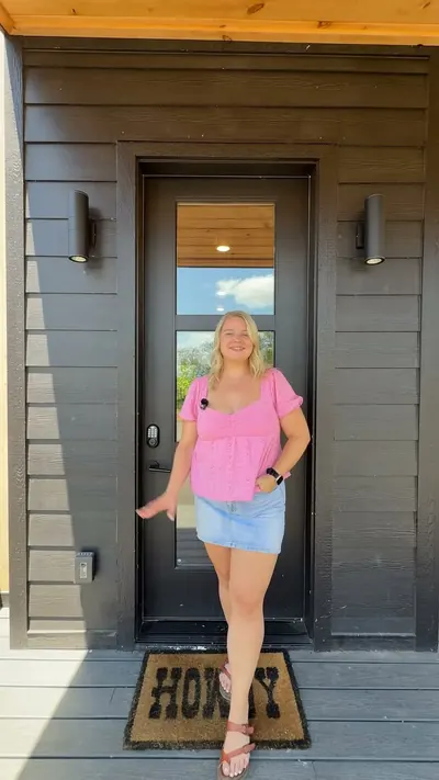 Guest in a pink top at a Smoky Mountain cabin front door with a HOME doormat
