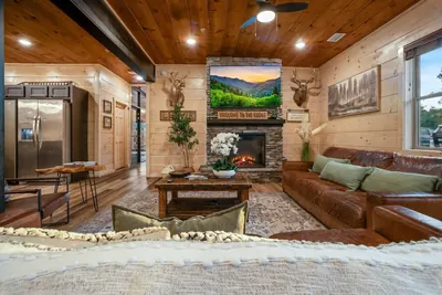 Open-plan cabin living room with stone fireplace and sectional sofa